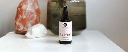 En flaske økologisk rosevann fra New Wellness står på et bord
